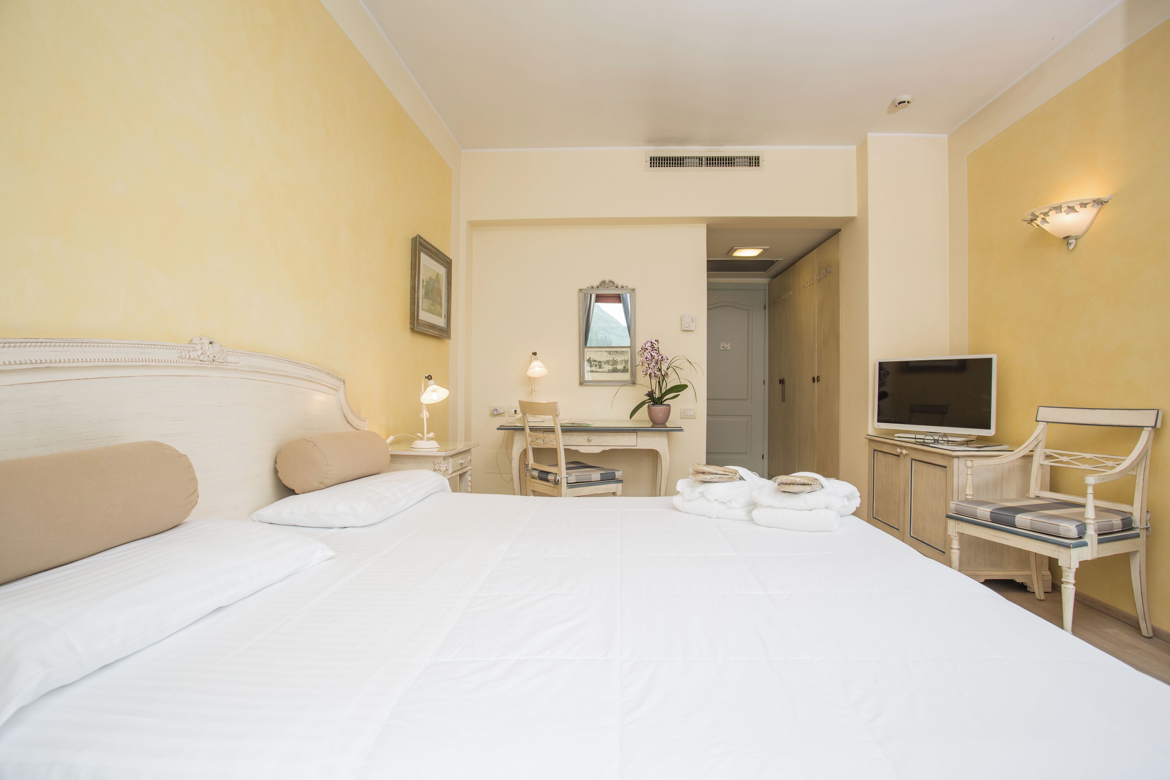 Ein Hotelzimmer mit einem großen Bett, einem Schreibtisch mit Stuhl, einem Fernseher und einem Spiegel an der Wand.