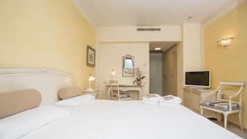 Ein Hotelzimmer mit einem großen Bett, einem Schreibtisch mit Stuhl, einem Fernseher und einem Spiegel an der Wand.