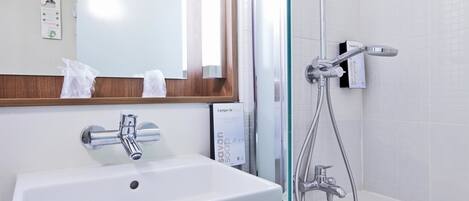Ein Badezimmer mit einem weißen Waschbecken, einem Spiegel, einer Dusche inklusive Duschbrause und einem Seifenspender.