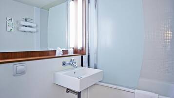 A bathroom with a white sink, a mirror, and a window.