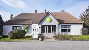 Un bâtiment avec un logo vert, une enseigne et une petite entrée.