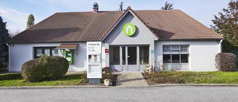 A building with a green logo, a signboard, and a small entrance.