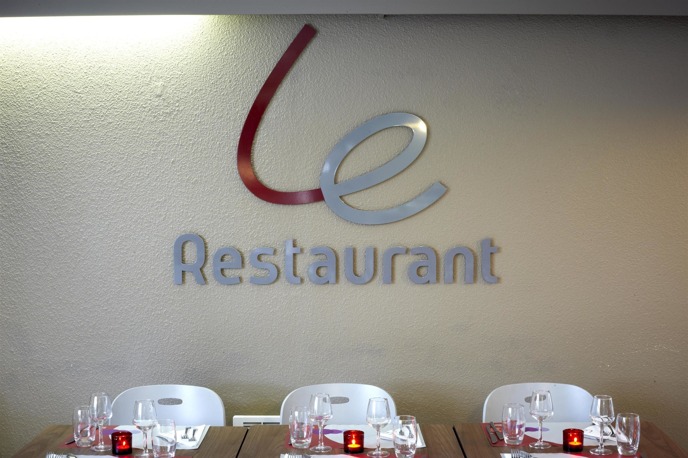 A restaurant sign with a modern design and a table set with glasses and cutlery.
