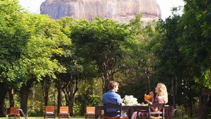 Zona de comedor junto a la piscina con vista a una gran formación rocosa.