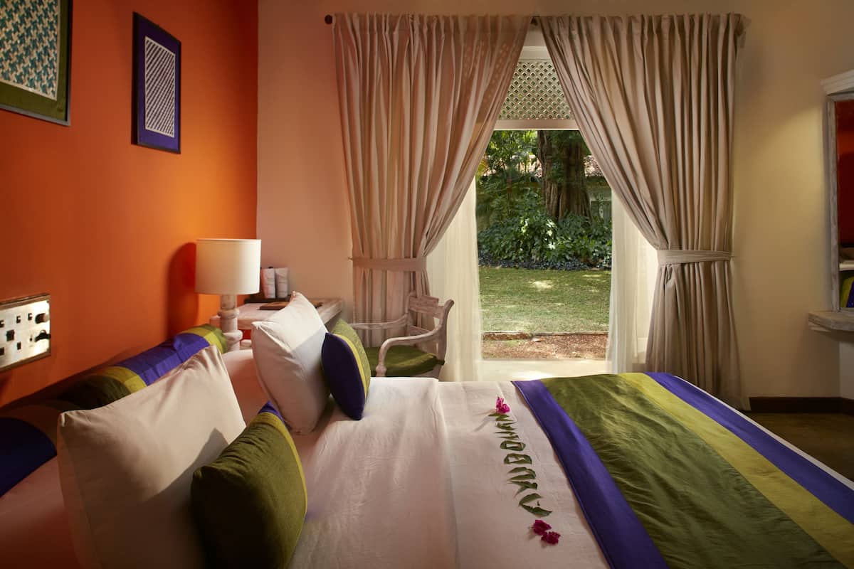 A hotel room with a bed, a chair, a desk, and a window with curtains.