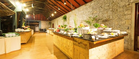 Una cocina amplia y bien iluminada, con pared de piedra y encimera de madera, que incluye varias plantas y utensilios de cocina.