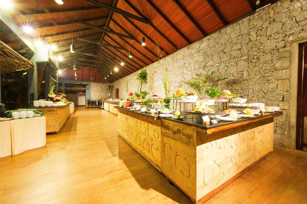 Una cocina amplia y bien iluminada, con pared de piedra y encimera de madera, que incluye varias plantas y utensilios de cocina.