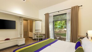 Habitación de hotel con cama, escritorio, silla, televisor montado en la pared y vista al exterior.