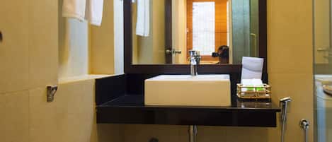 Un baño pequeño con lavamanos blanco, espejo, toallero y ducha.