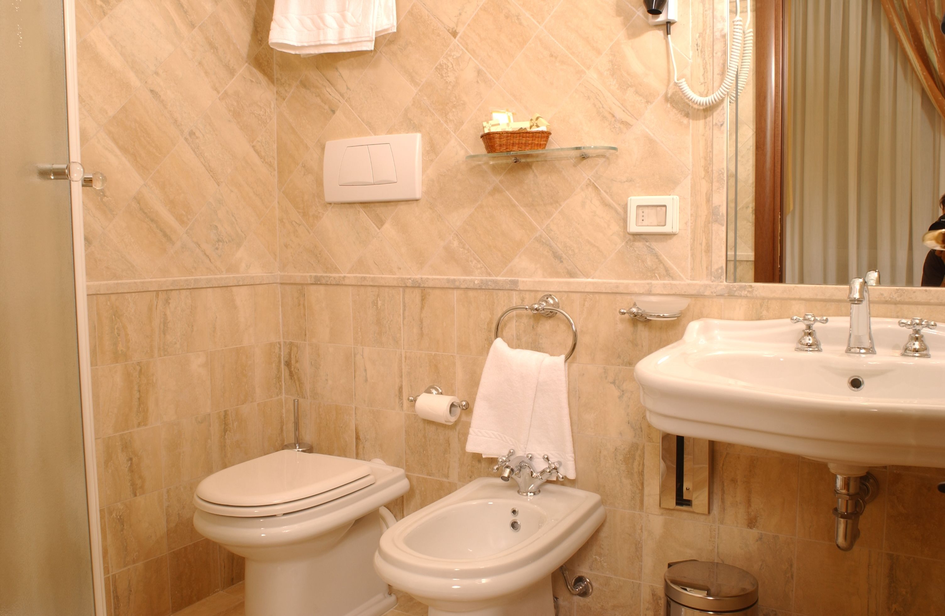 Un bagno con il water, bidet, lavabo e uno specchio.
