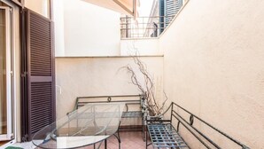 A small outdoor patio with a glass table and metal benches, a door, and a potted plant. - Il Gattopardo Relais (Rome)