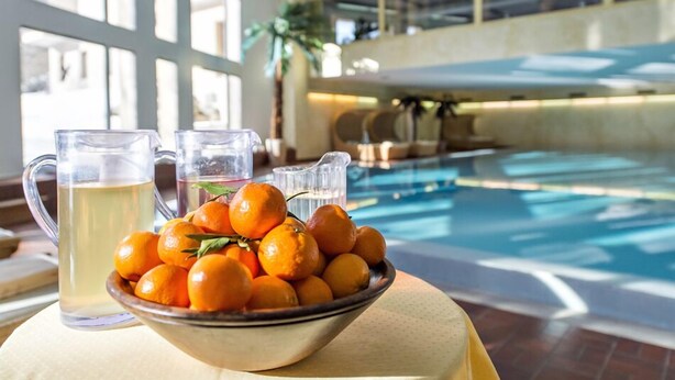 A poolside setting with a bowl of oranges and pitchers of beverages. - Quadratscha Hotel (Samedan)
