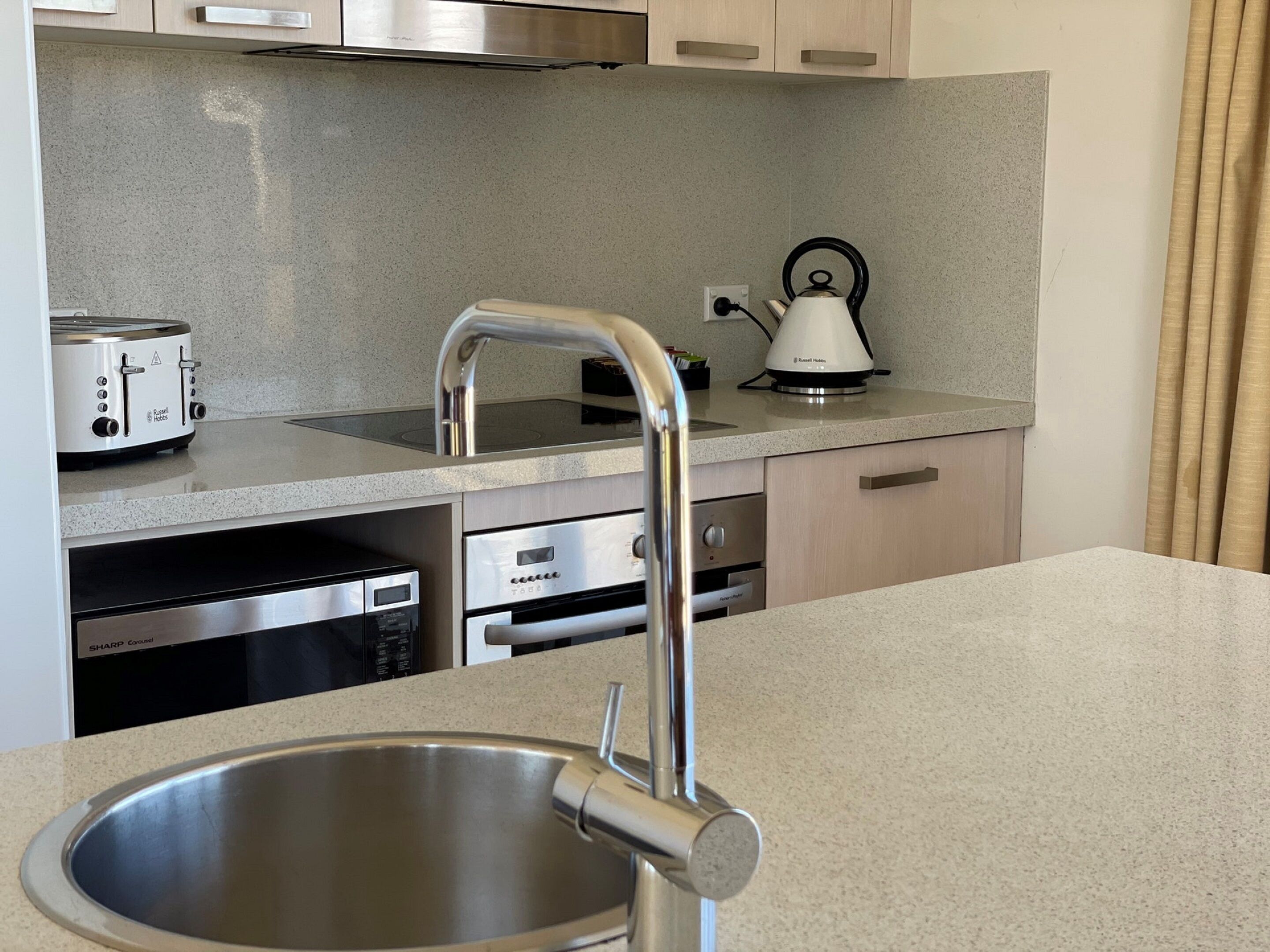 Una cocina moderna con un lavamanos de acero inoxidable, un hervidor y un tostador.