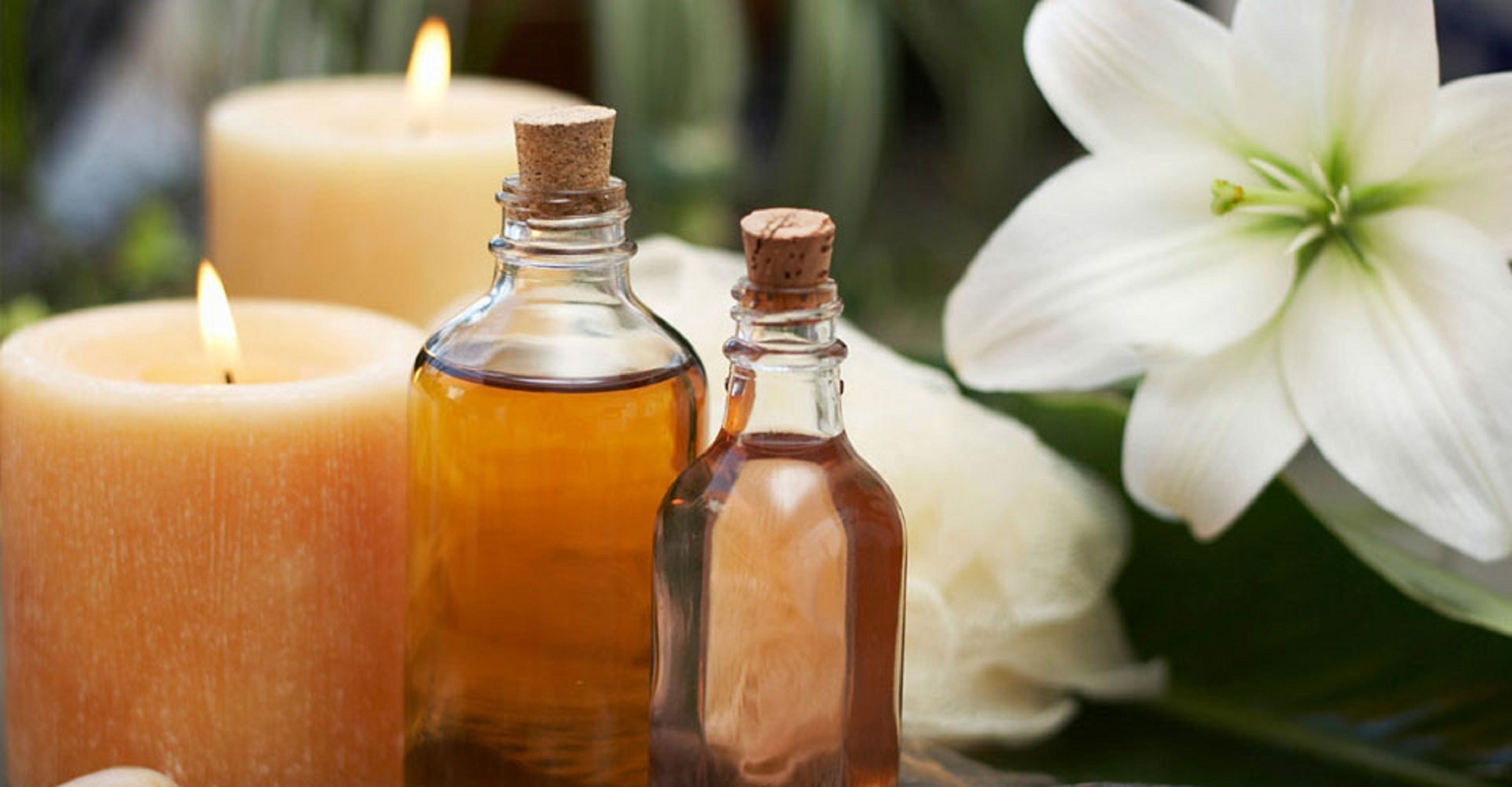 A candle, two small bottles, and a white flower.