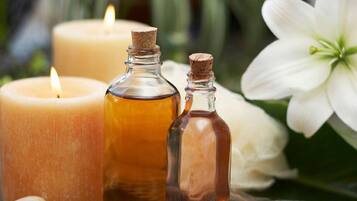 A candle, two small bottles, and a white flower.