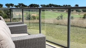 Un balcón con mobiliario de mimbre y vistas a un campo de golf.