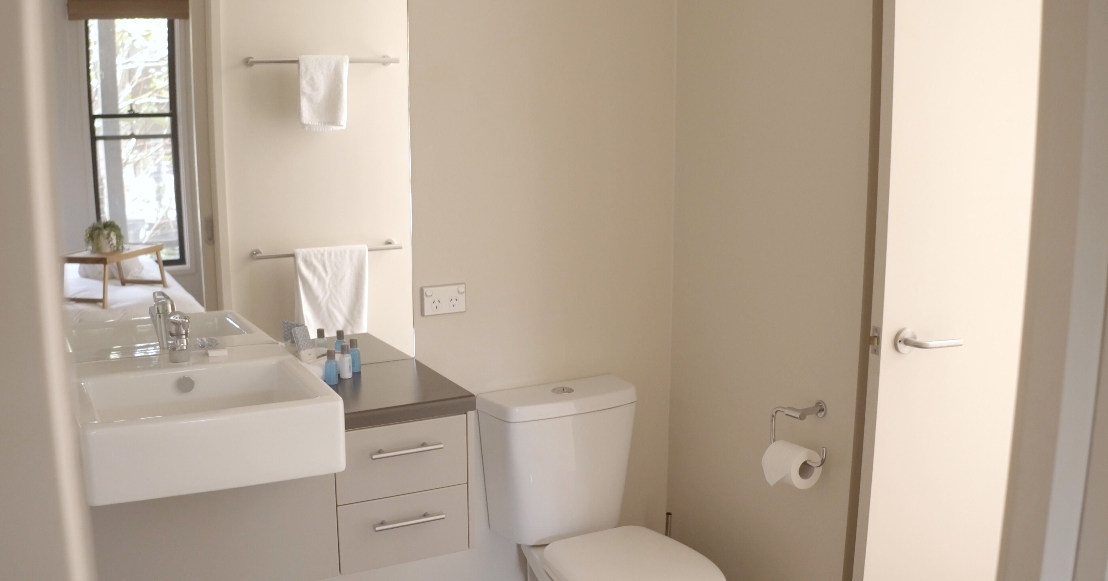 Et badeværelse med håndvask, toilet og håndklædestativ.