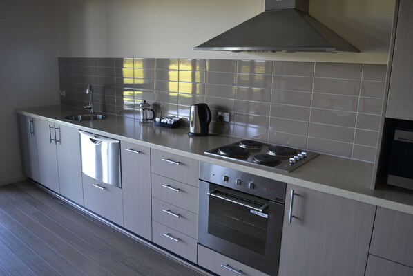 A modern kitchen with stainless steel appliances, grey cabinets, and a tiled backsplash.