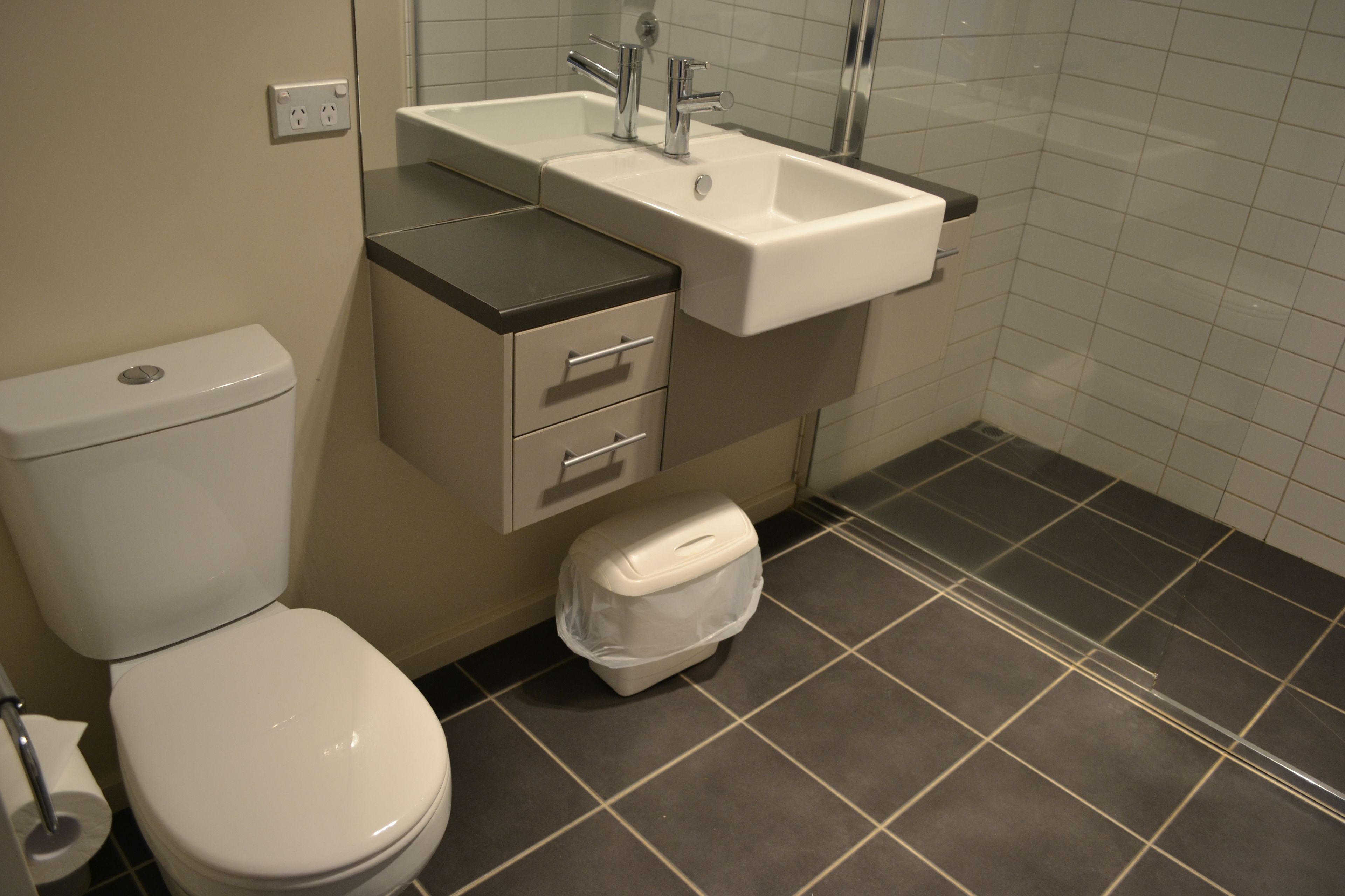 Une salle de bain comprenant des toilettes, un lavabo et un meuble de rangement.