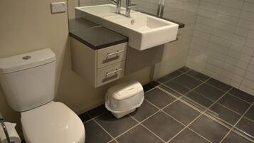 Een badkamer met toilet, wastafel en opbergkast.