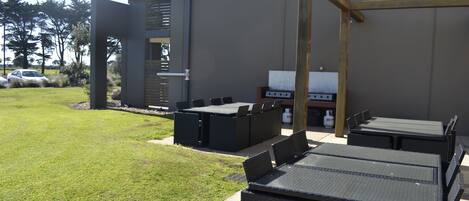 An outdoor patio area with a grill, seating, and a pergola structure.