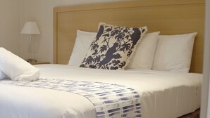 A neatly made bed with a rolled white towel, a patterned pillow, and a white pillow. - Barwon Heads Resort at 13th Beach (Connewarre)
