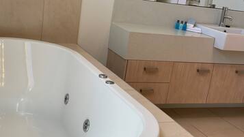 A modern bathroom with a large bathtub, a sink, and wooden cabinets.