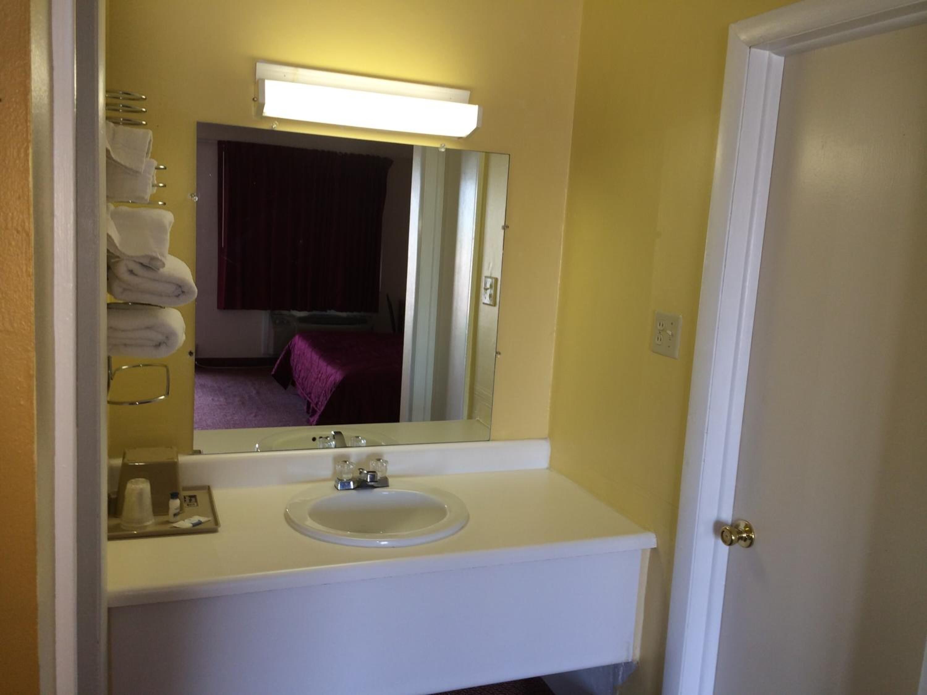 Un baño con un lavamanos blanco, un espejo y un perchero para toallas.