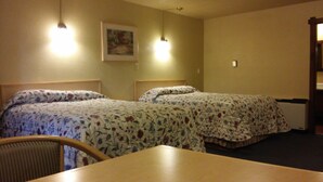 A hotel room with two single beds, a wooden table, and a chair. - Budget Host Longhorn Motel (Byers)