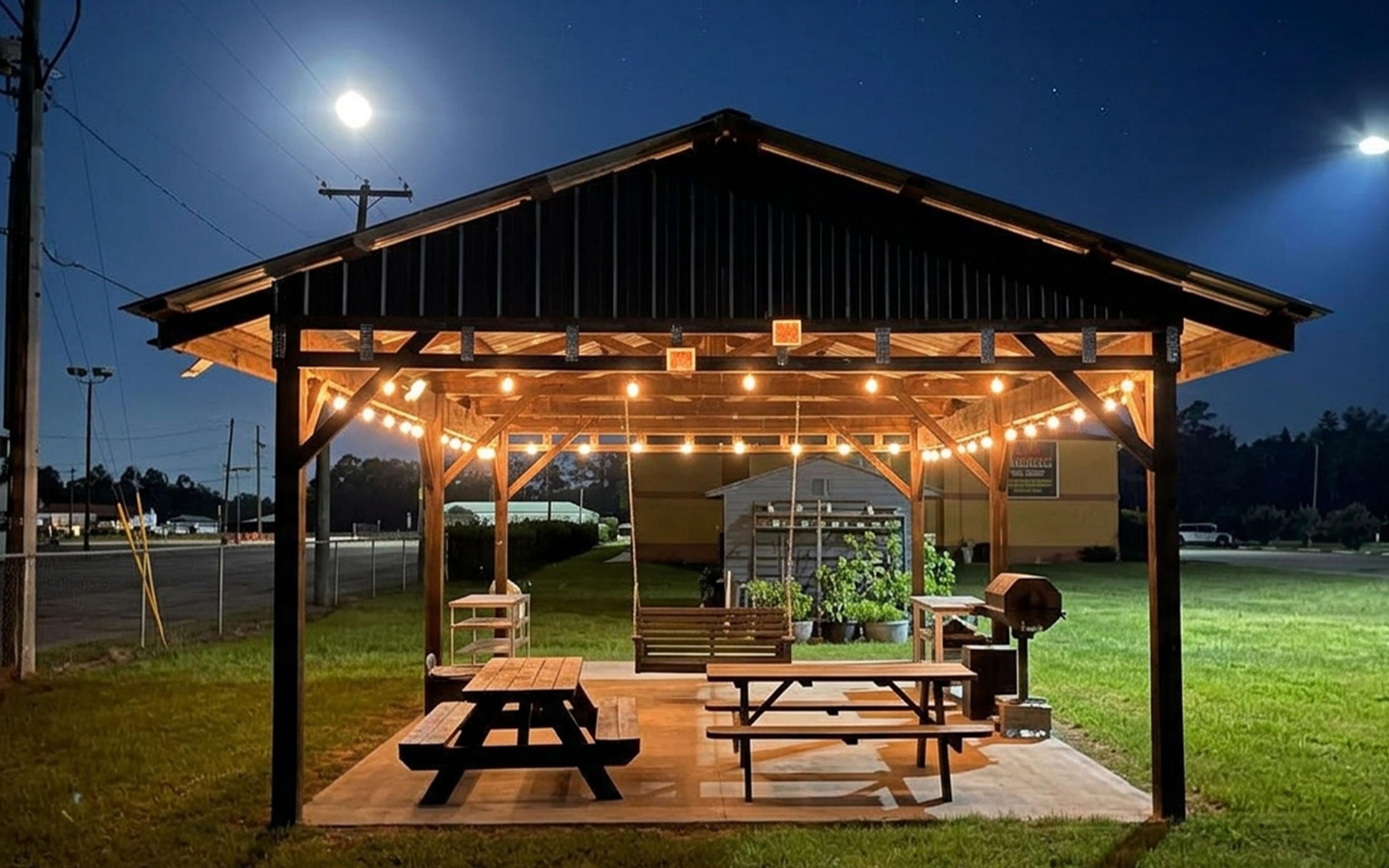 A covered outdoor seating area with picnic tables and string lights.