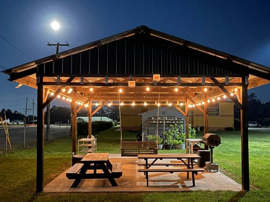 Ein überdachter Außenbereich mit Picknicktischen und Lichterketten.