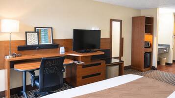 A hotel room with a bed, desk, chair, television, and a mirror.