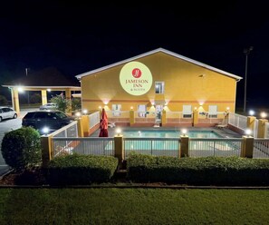Un Jameson Inn & Suites con piscina, area salotto esterna e facciata ben illuminata.