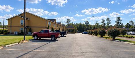 A parking lot with a yellow building, a red truck, and a clear blue sky.