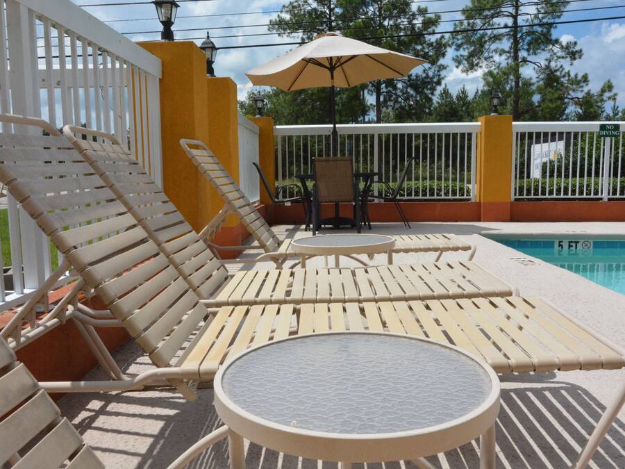 A poolside area with lounge chairs and a table, a 'No Diving' sign, and a pool with a '5 FT' depth marker.
