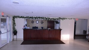 Un comptoir d’accueil avec un revêtement de couleur brun foncé, une plante en pot et une horloge murale.