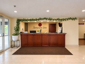 A reception desk with a 'Jameson Inn' sign, a potted plant, and a 'Meeting Room' sign.