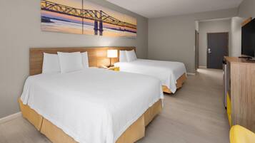 Habitación de hotel con dos camas, un escritorio, un televisor y un cuadro de un puente.