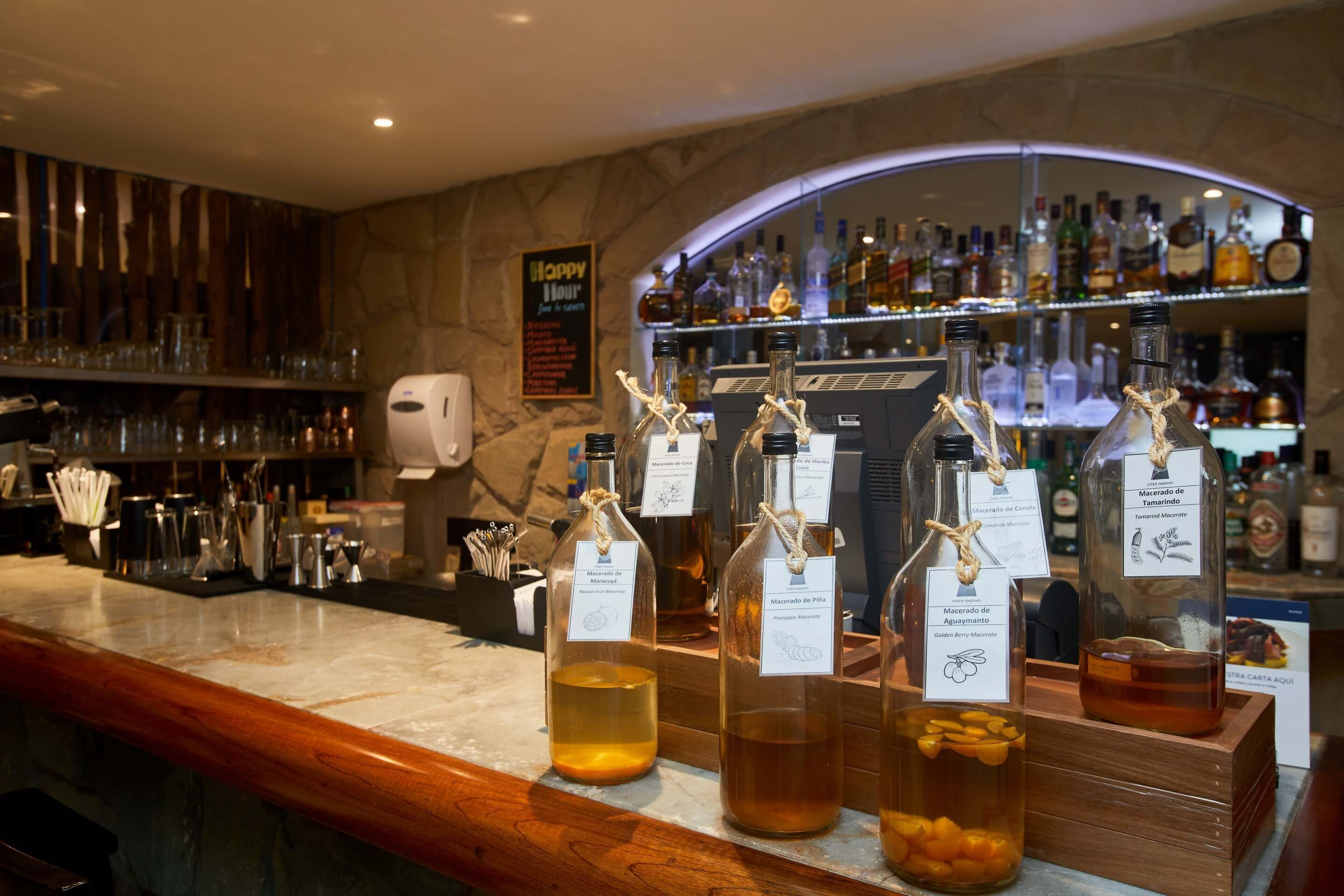 A bar area with various bottles of liquor, a sign reading "Happy Hour," and a marble countertop.