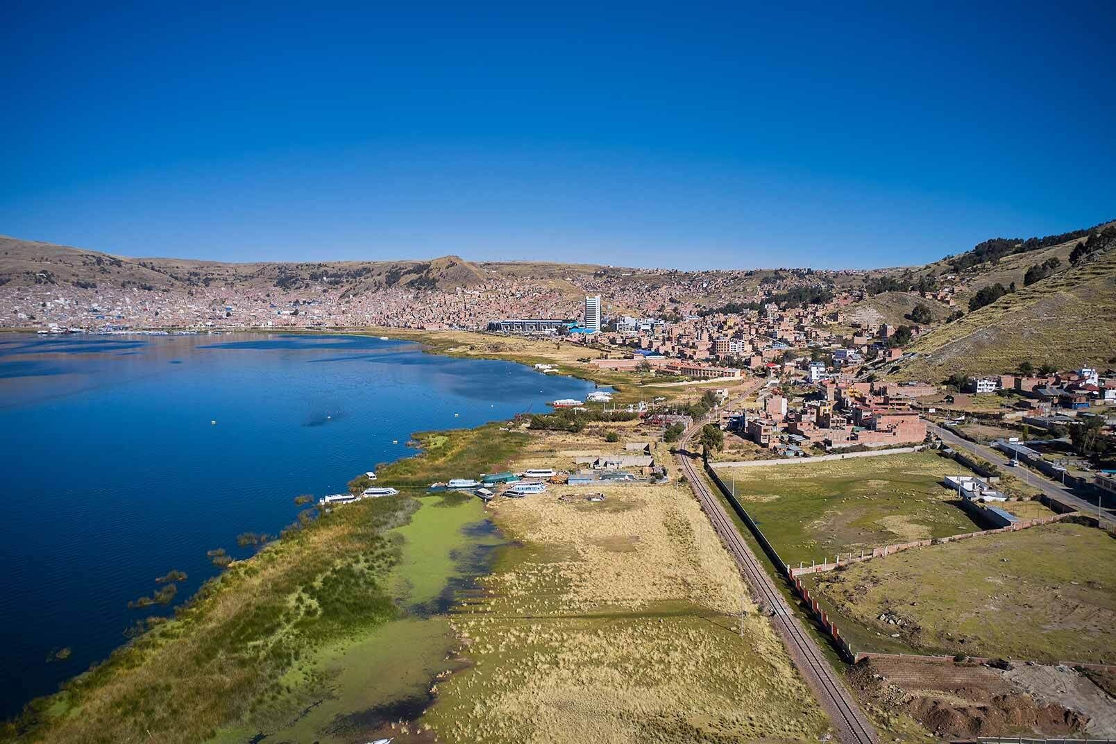 An aerial view of a coastal town with a large body of water, a bridge, and a railway line.