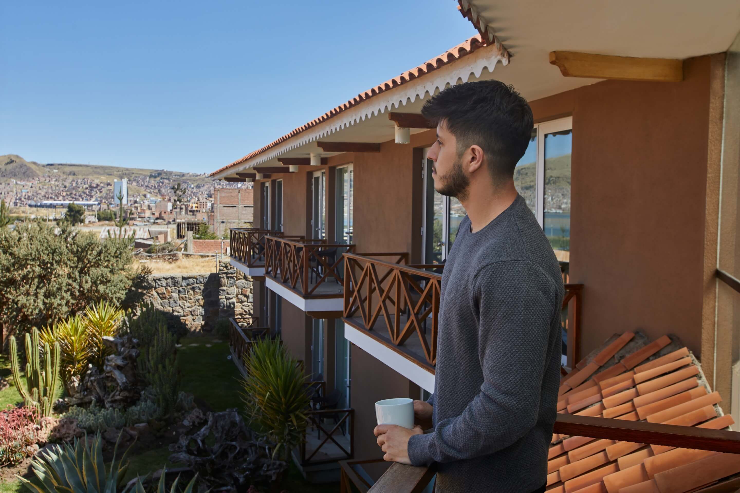 A man standing on a balcony with a view of a cityscape.