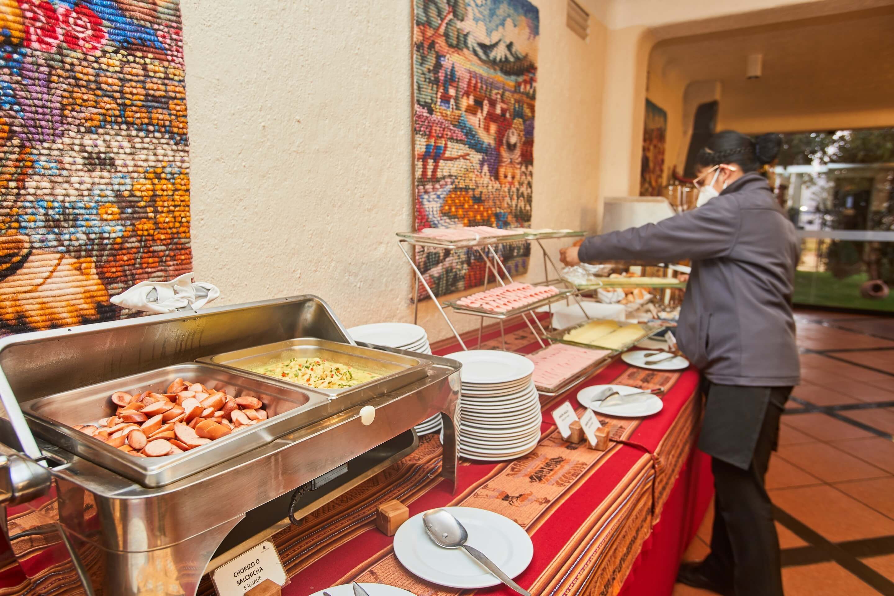 A buffet setup with various food items and a staff member serving.
