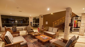 A spacious lobby with wooden furniture, a patterned rug, and a staircase in the background. - Casa Andina Premium Puno (Puno)