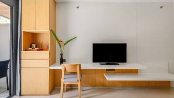A modern living room with a wooden cabinet, a flat-screen TV, a chair, and a plant.