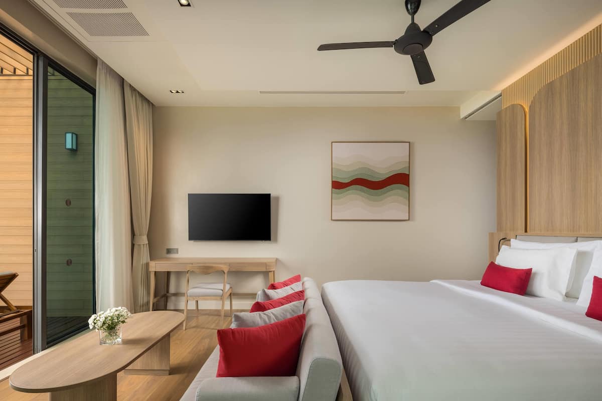 A modern hotel room with a bed, a desk, and a TV.