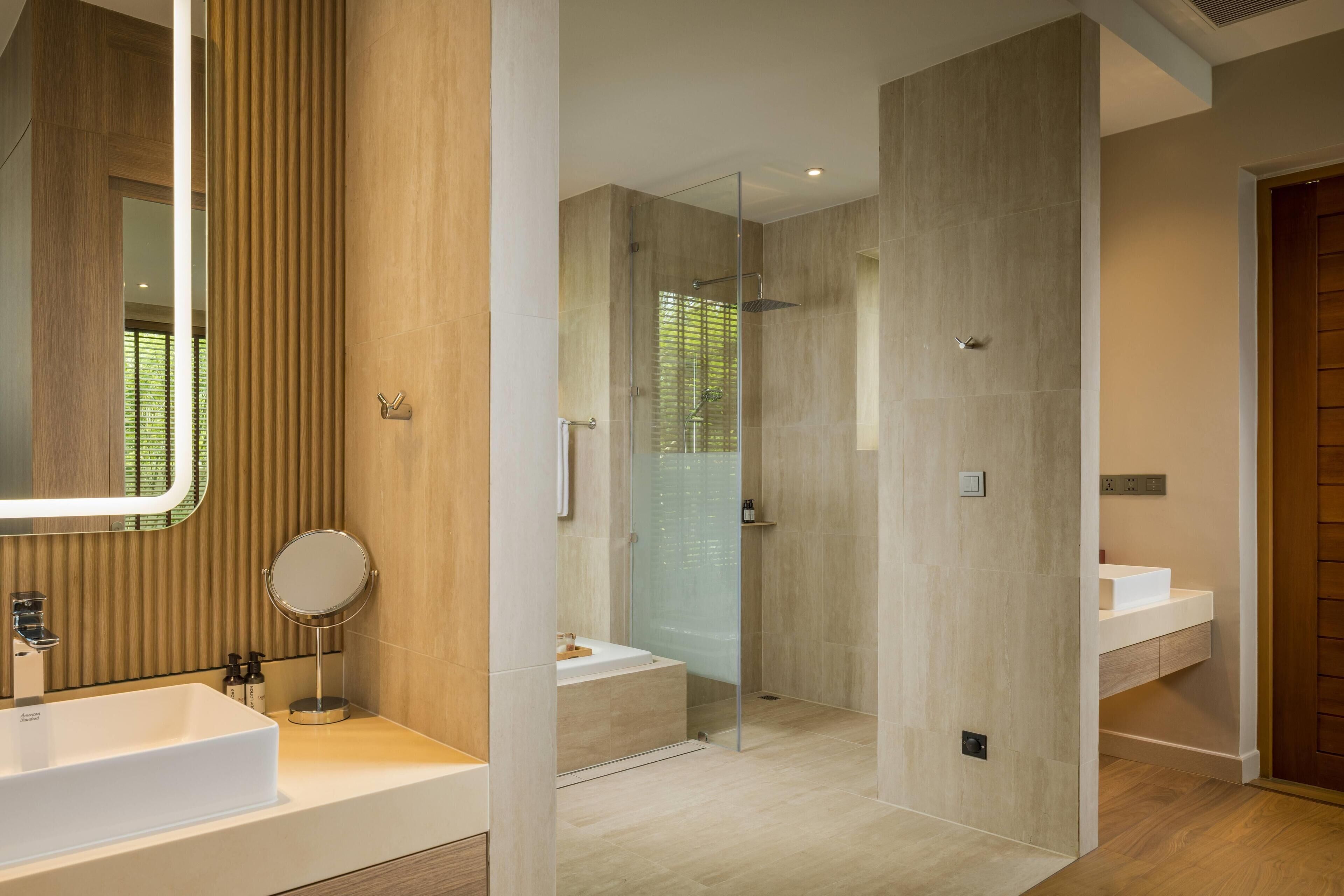 A modern bathroom with a large mirror, a bathtub, and a glass-enclosed shower.