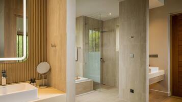 A modern bathroom with a large mirror, a bathtub, and a glass-enclosed shower.