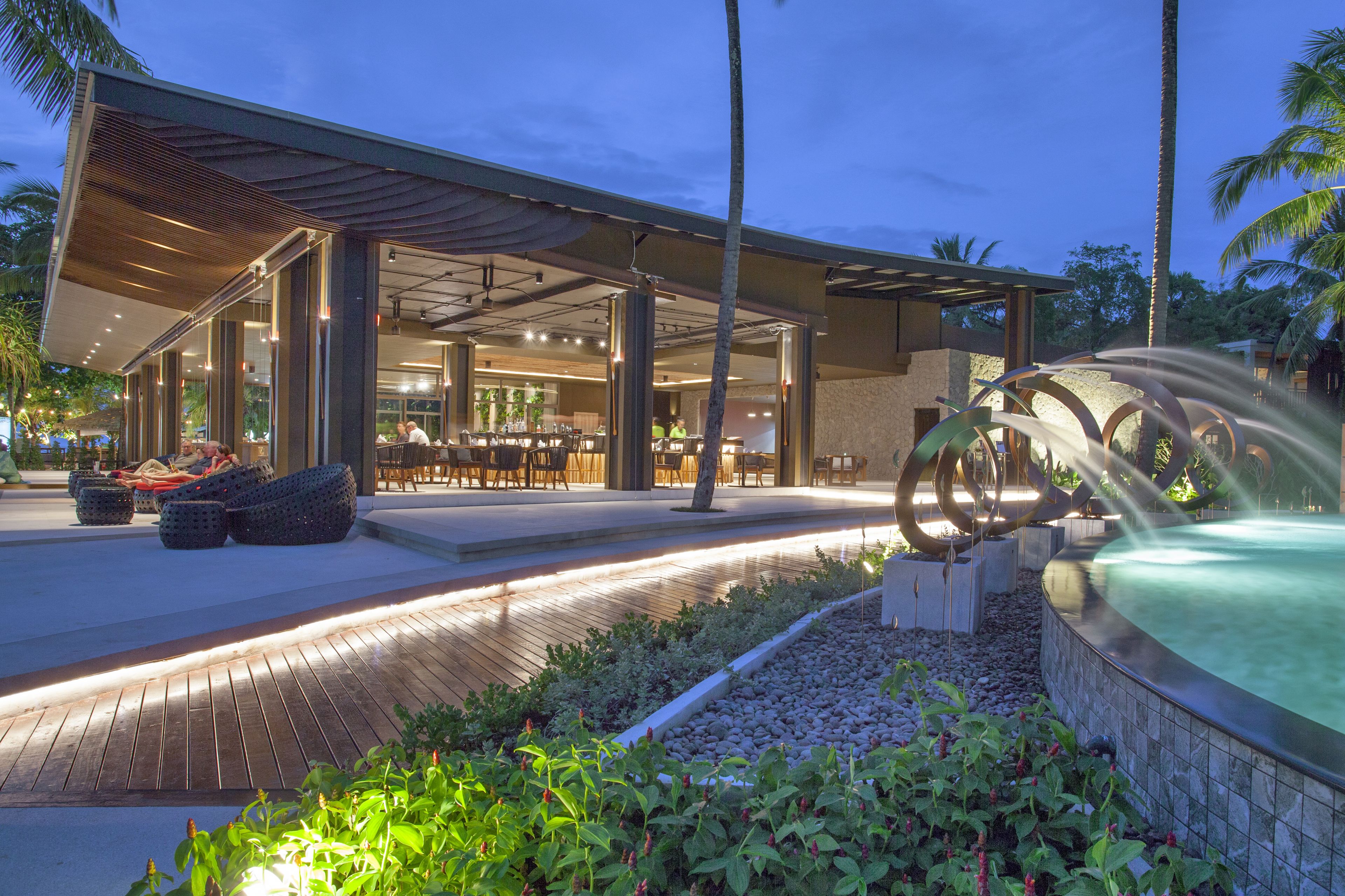 Un hotel moderno con zona de estar exterior, piscina y patio bien iluminado.