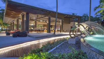 Un hotel moderno con zona de estar exterior, piscina y patio bien iluminado.