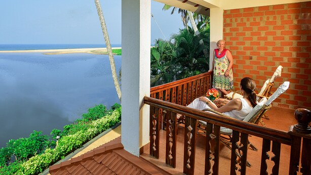 A balcony with a view of the sea, a brick wall, and a wooden railing. - Beach and Lake Ayurvedic Resort (Thiruvananthapuram)